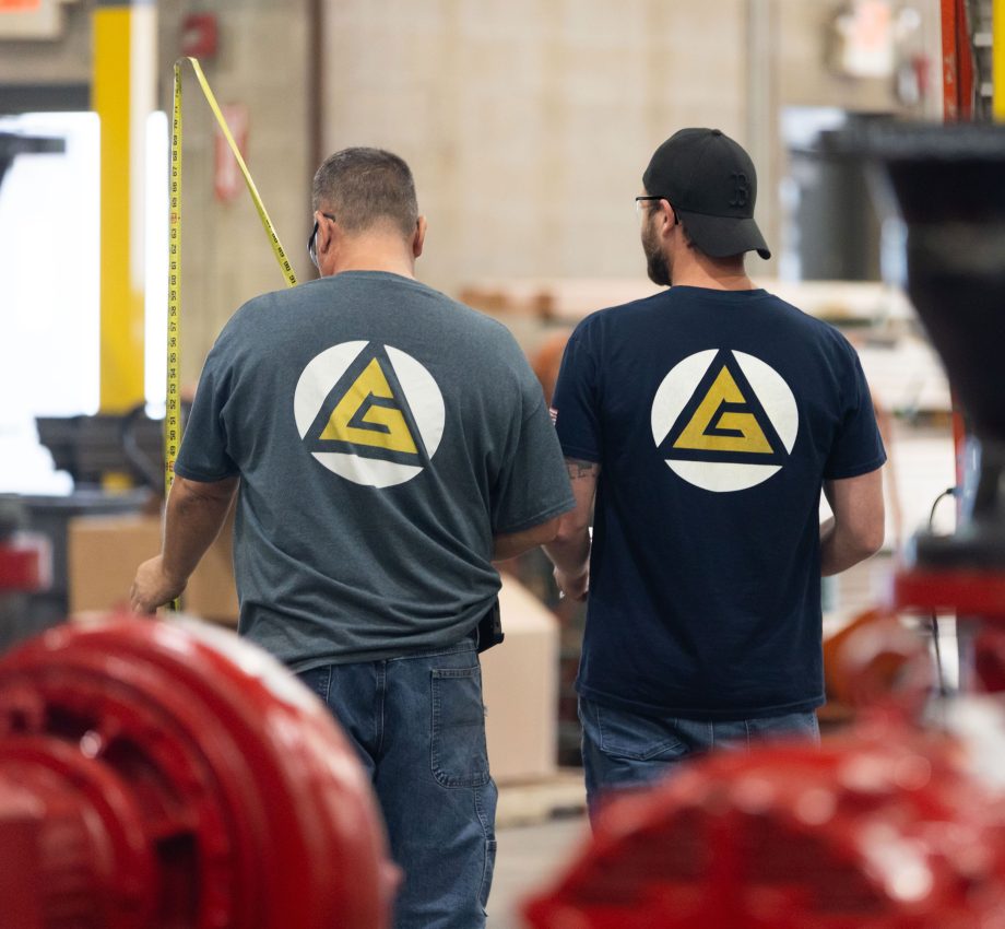 Two man standing next to each other, working in warehouse, wearing TG Gallagher shirts