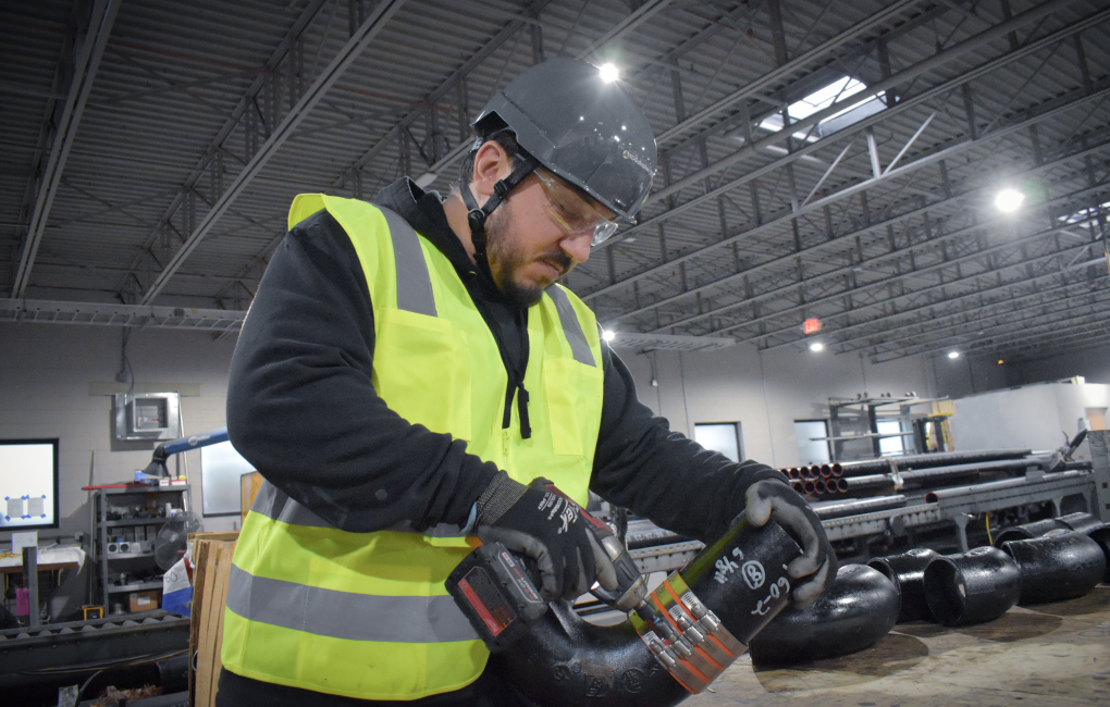 Man in construction gear, drilling into piece of equipment