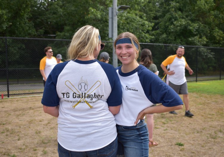 Two women posing in TG Gallagher Whiffle Ball Tournament shirts