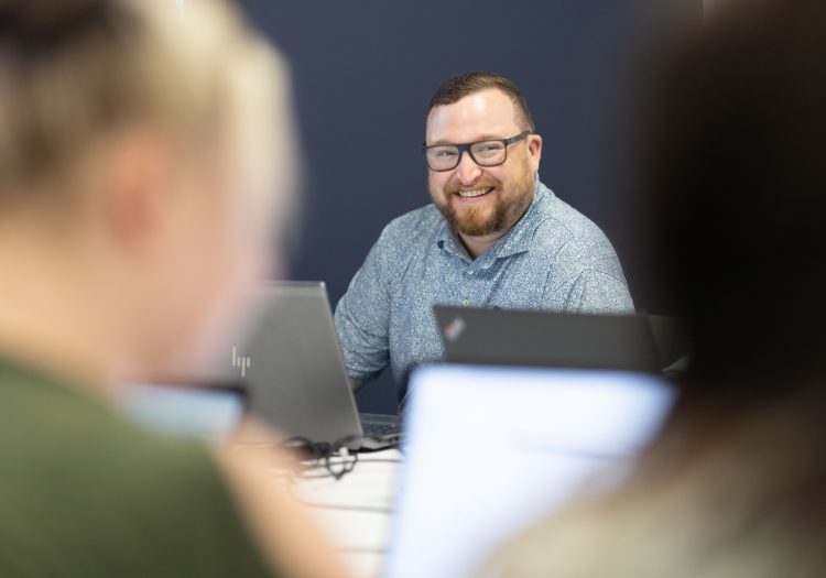 Man sitting at a table on laptop, smiling