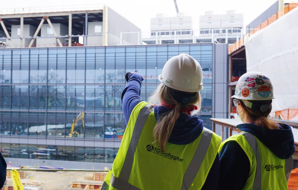 Two women in construction gear, pointing at a building on construction site