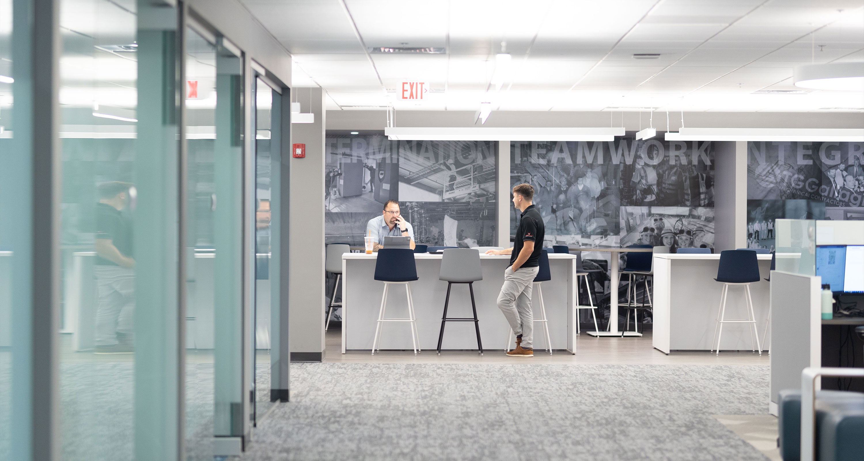 Two men standing at a table talking at the TG Gallagher office