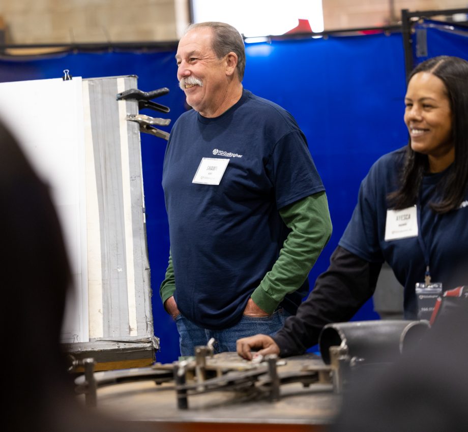 Man and woman standing next to equipment, smiling